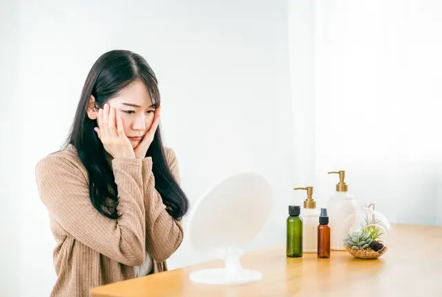 鏡を見て悩む女性の画像