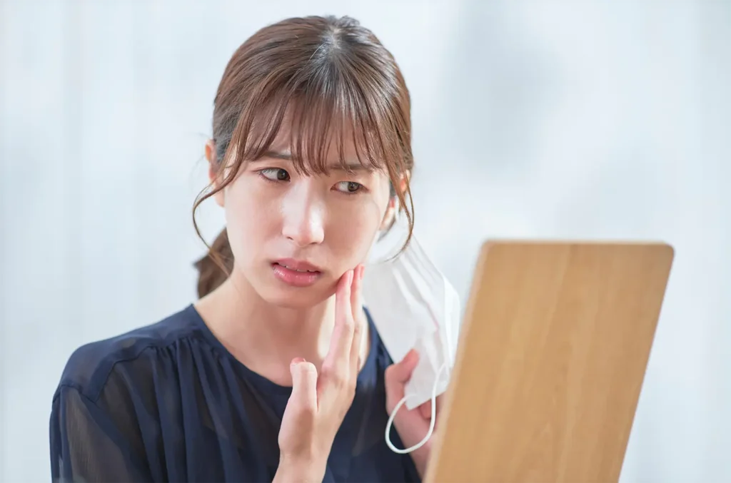 フェイスラインを気にして鏡を見る女性