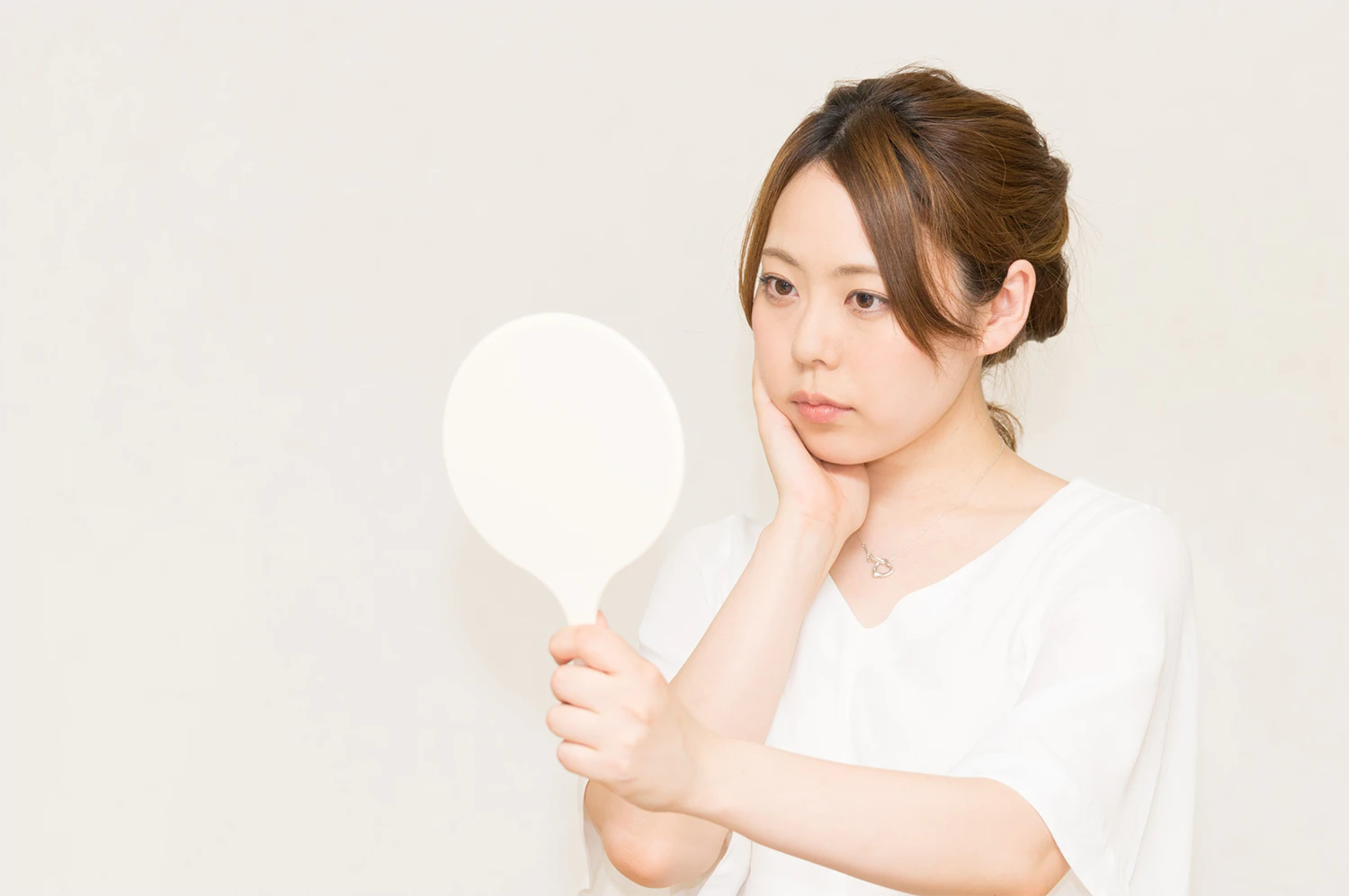 鏡で顔を見ている女性