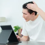 鏡を見て生え際を気にしている男性