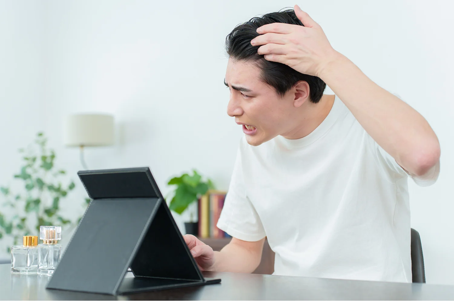 鏡を見て生え際を気にしている男性