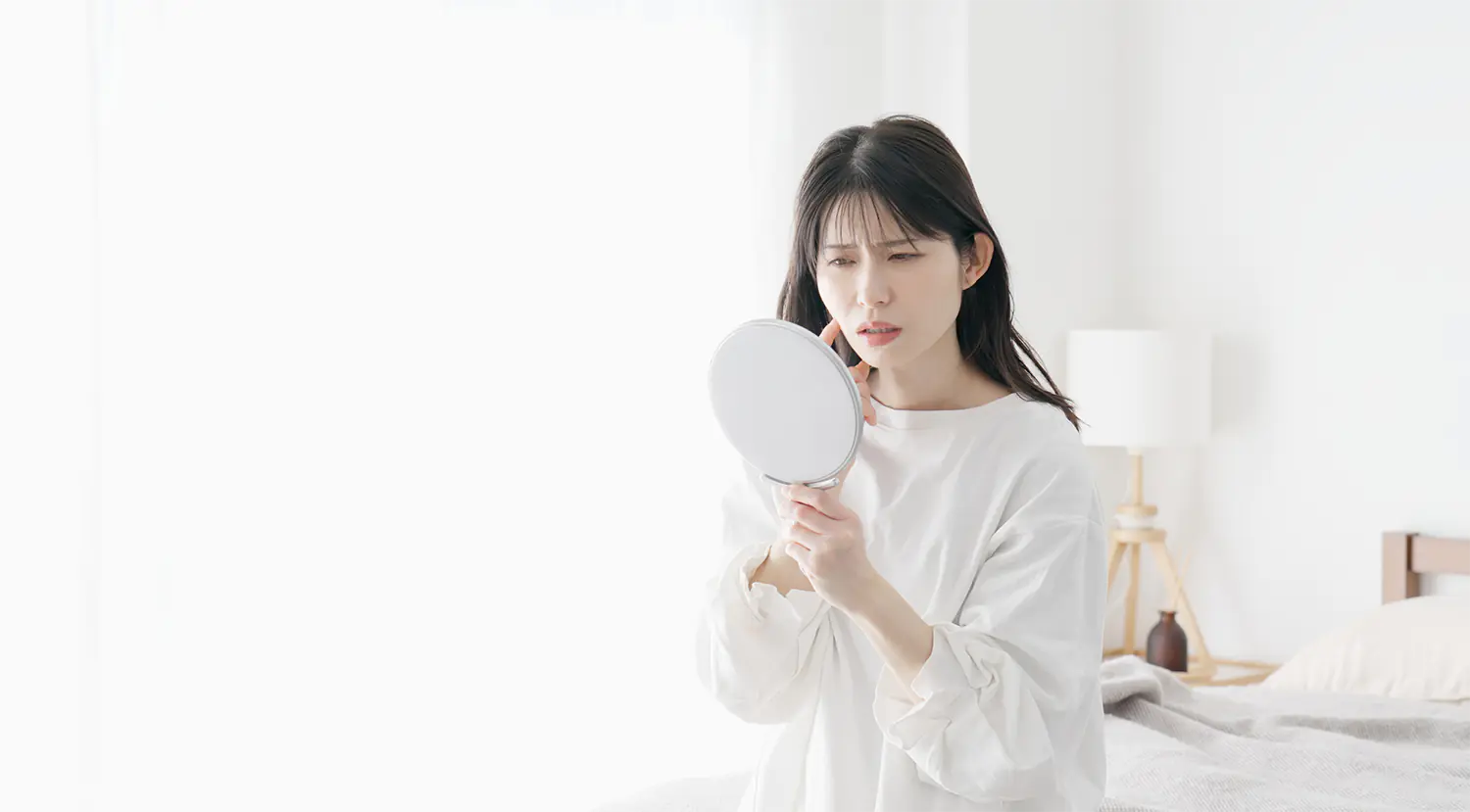 鏡をみてできものをきにする女性