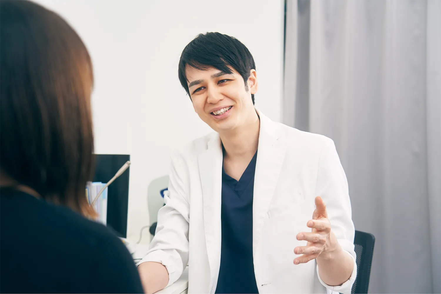 ニキビ跡の状態を診察しながら治療方針を説明する医師