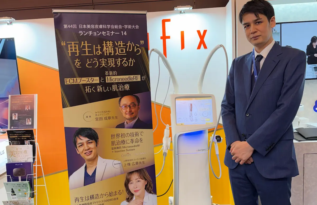 日本美容皮膚科学会のランチョンセミナー会場でブレッシングの機器と並ぶ院長